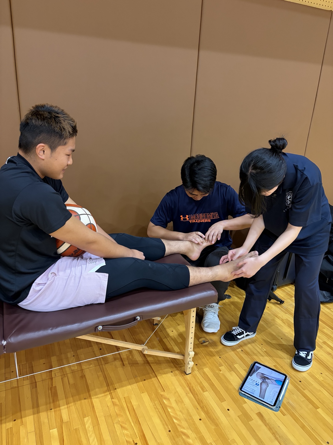 選手の協力を得て足関節の触診を実践する学生たち